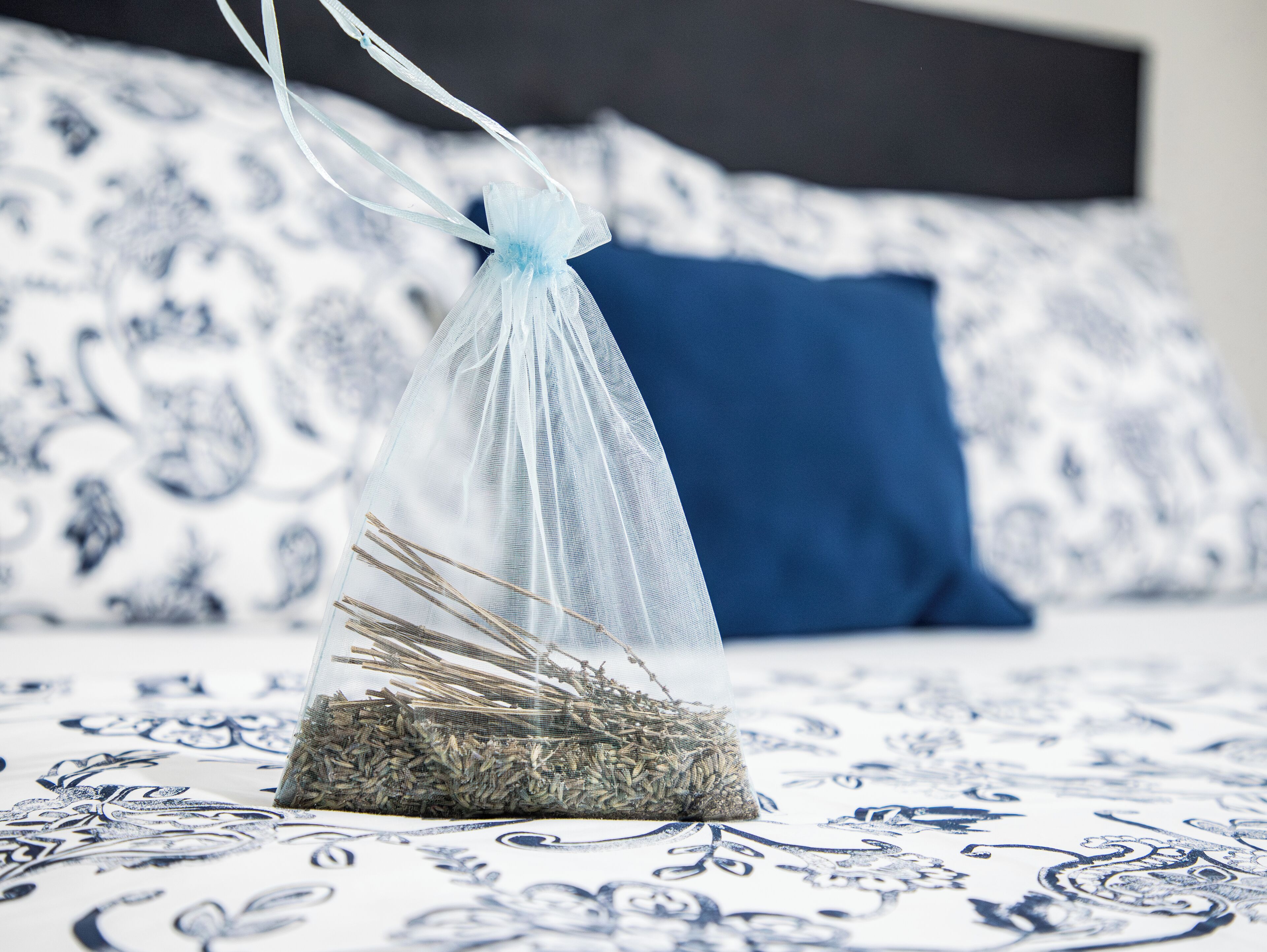 A bed with a patterned bedspread, a blue pillow, and a decorative item on the bed.