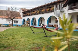 Un patio con una hamaca, una piscina y un edificio con puertas arqueadas.