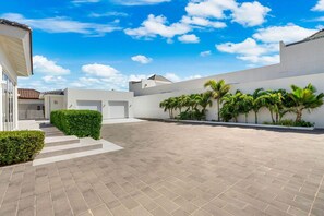 A spacious courtyard with a paved floor, surrounded by white walls and palm trees. - 4 BR Paradise with Private Pool! (Noord)
