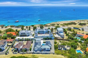 A coastal residential area with houses, a swimming pool, and boats in the water. - Modern 4BR Pool Villa, Walk to Boca Catalina Beach (Noord)