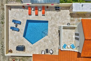 An outdoor swimming pool with lounge chairs and a barbecue area.