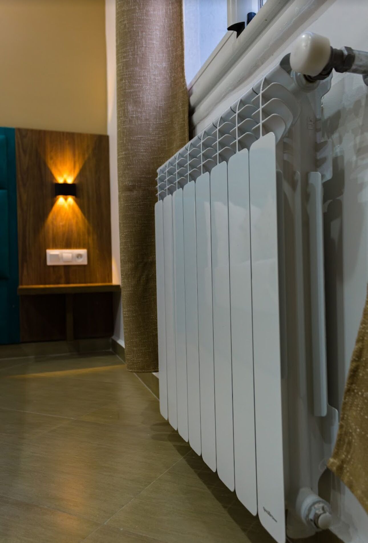 A modern bathroom with a white radiator, wooden wall paneling, and a towel rack.