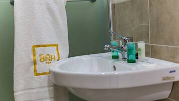 Ein Badezimmer mit einem weißen Waschbecken, einem Handtuch mit einem Logo und Toilettenartikeln auf dem Waschbecken.