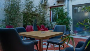 A small outdoor seating area with a wooden table and black and red chairs. - HNR Hotel - El Hamma (Algiers)