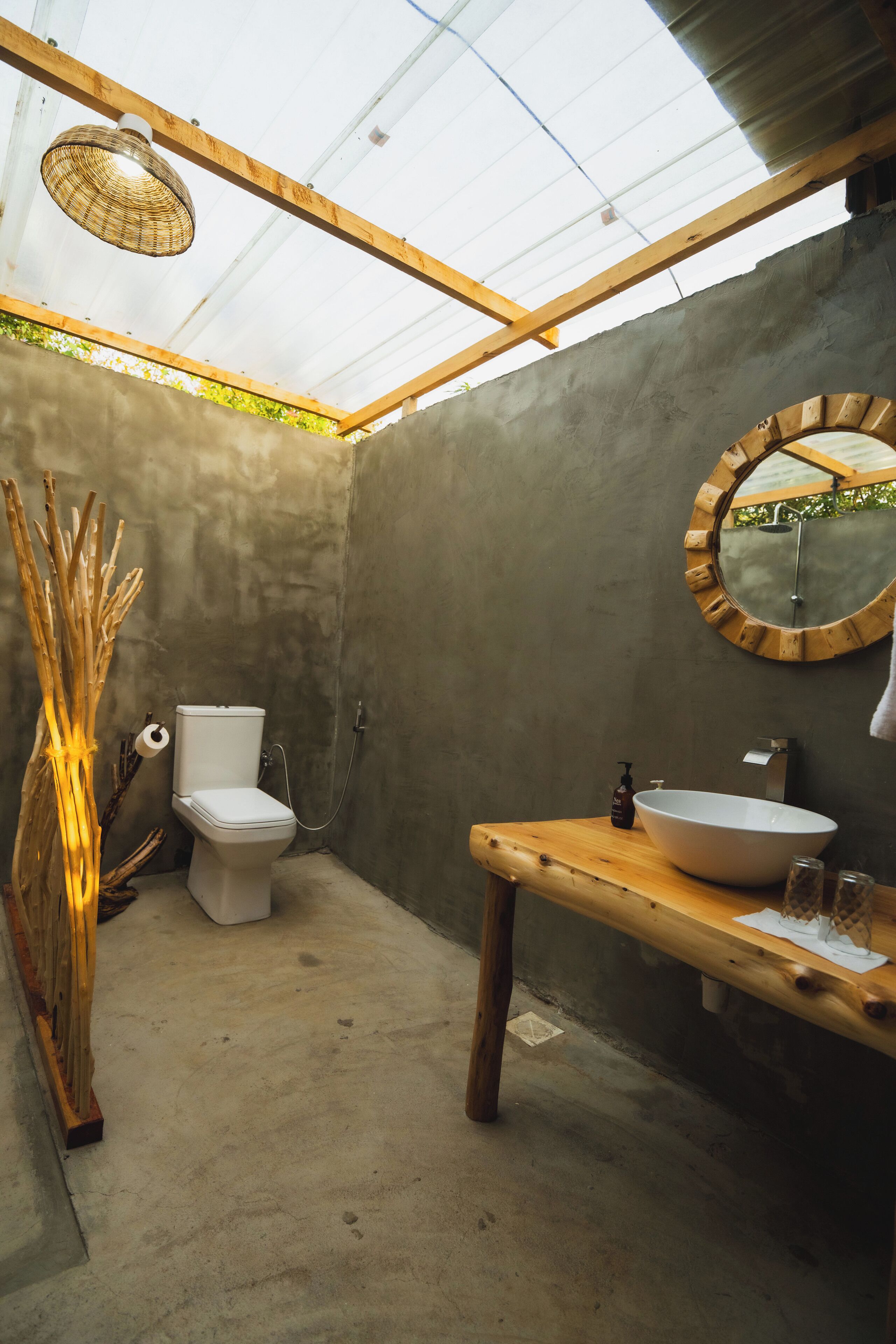 Een kleine badkamer met toilet, wastafel en een houten bankje.
