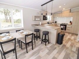 Una cocina moderna con una isla central, taburetes de bar y una mesa de comedor para cuatro.