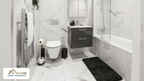Une salle de bain moderne équipée de toilettes, d’un lavabo et d’une baignoire.