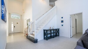 Ein geräumiger Wohnbereich mit Treppe, einer Konsole und einer Tür zu einem weiteren Raum.