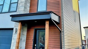 A multi-story building with a mix of siding and brickwork, featuring large windows and a visible garage door. - Your Halifax Getaway – Relax & Explore (Halifax)