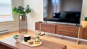 A modern living room with a wooden bench, a TV, and decorative items on a tray. - Your Halifax Getaway – Relax & Explore (Halifax)