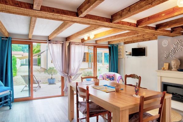 Un coin repas avec une table et des chaises en bois, un téléviseur fixé au mur et une cheminée.