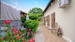 Un étroit sentier mène à un bâtiment doté d’un espace de repos abrité et d’une rangée de portes en bois.