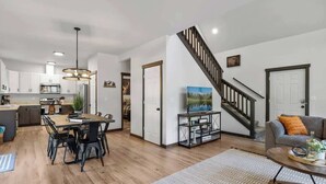 Un salon moderne avec un escalier, un coin repas et une cuisine.