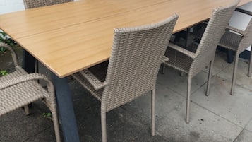 Una mesa rectangular al aire libre con seis sillas de mimbre.
