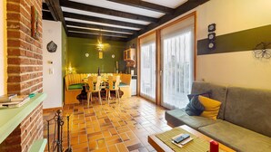 A dining area with a brick wall, wooden ceiling beams, and a green wall with a clock.