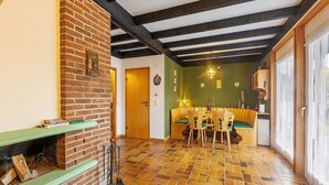 A dining area with a brick fireplace, a wooden ceiling, and a tiled floor.