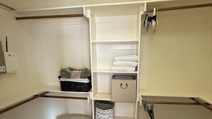 A walk-in closet with open shelving, storage bins, and hanging space.