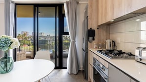 Een moderne keuken met uitzicht op de stad, een eethoek met tafel en stoelen, en een balkon met gordijnen.