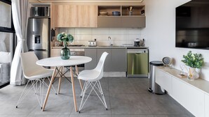Een moderne keuken met witte stoelen, een ronde tafel, een magnetron, een spoelbak en een vaatwasser.