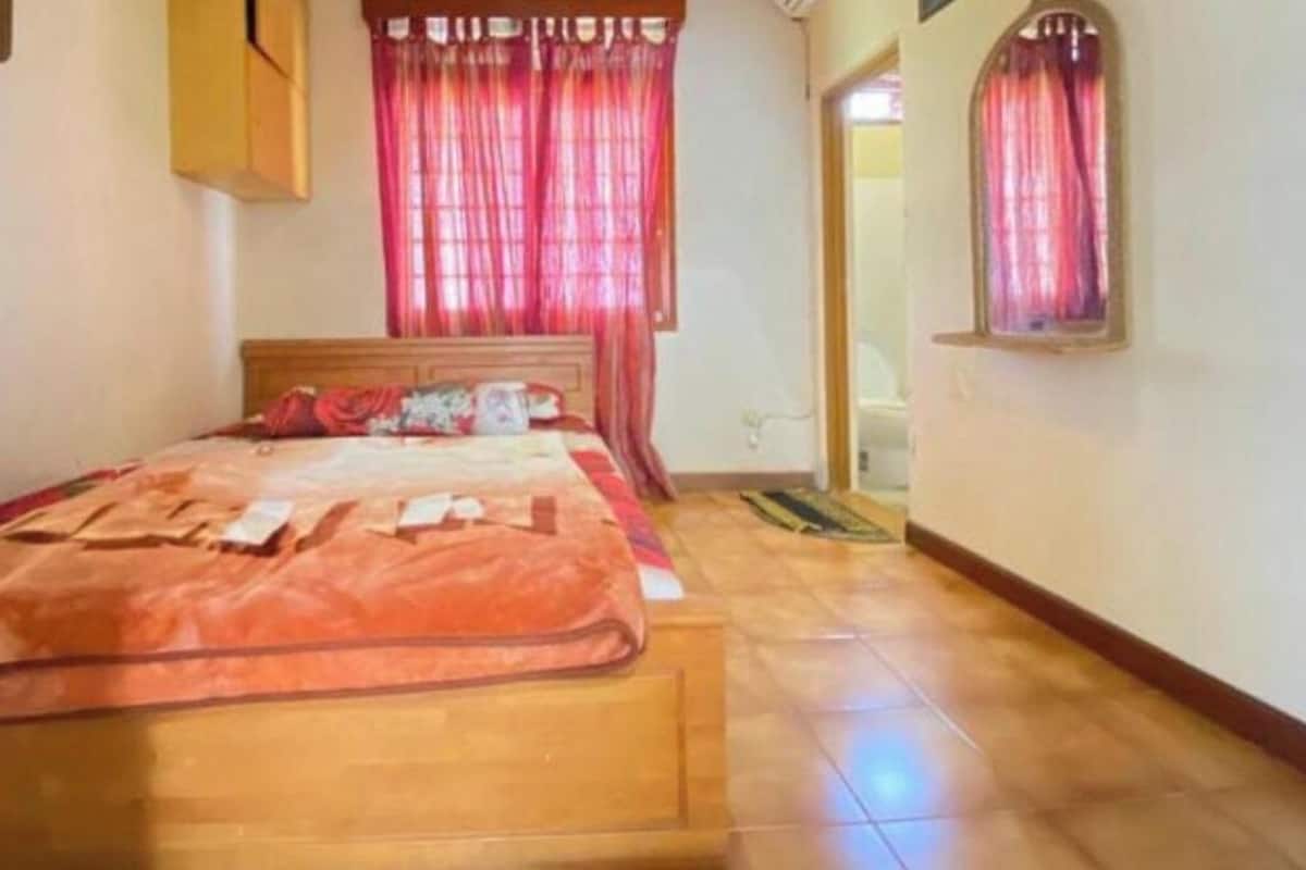 A bedroom with a wooden bed, red curtains, and a small window.