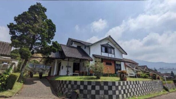 A residential house with a sloped roof, a front porch, and a well-maintained lawn. - Hotel O Bougenville Resort (Cipanas)