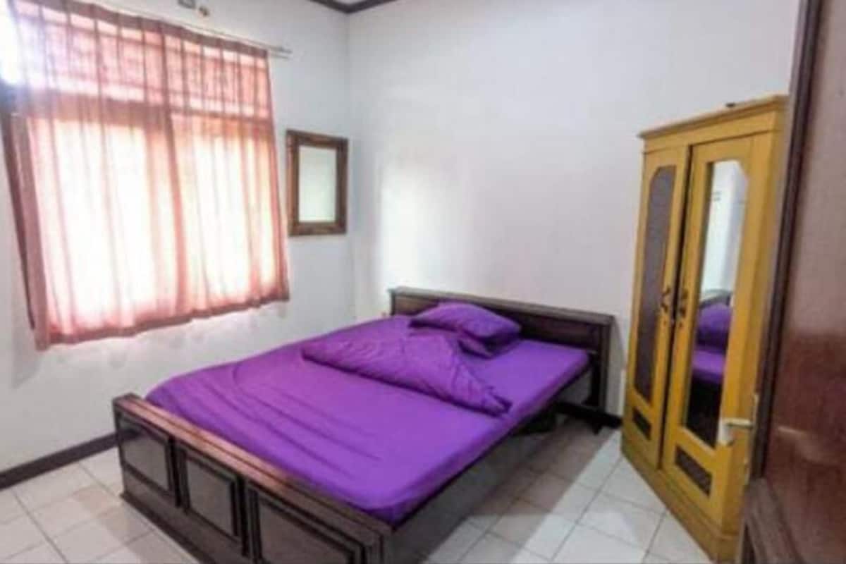 A bedroom with a bed, a wardrobe, and a window with curtains.