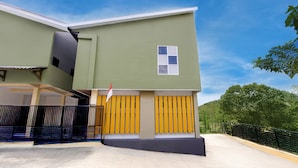 A modern building with a green facade, a small window, and a yellow gate.