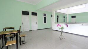 A room with a green wall, white doors, a wooden table with chairs, and a vase with flowers.