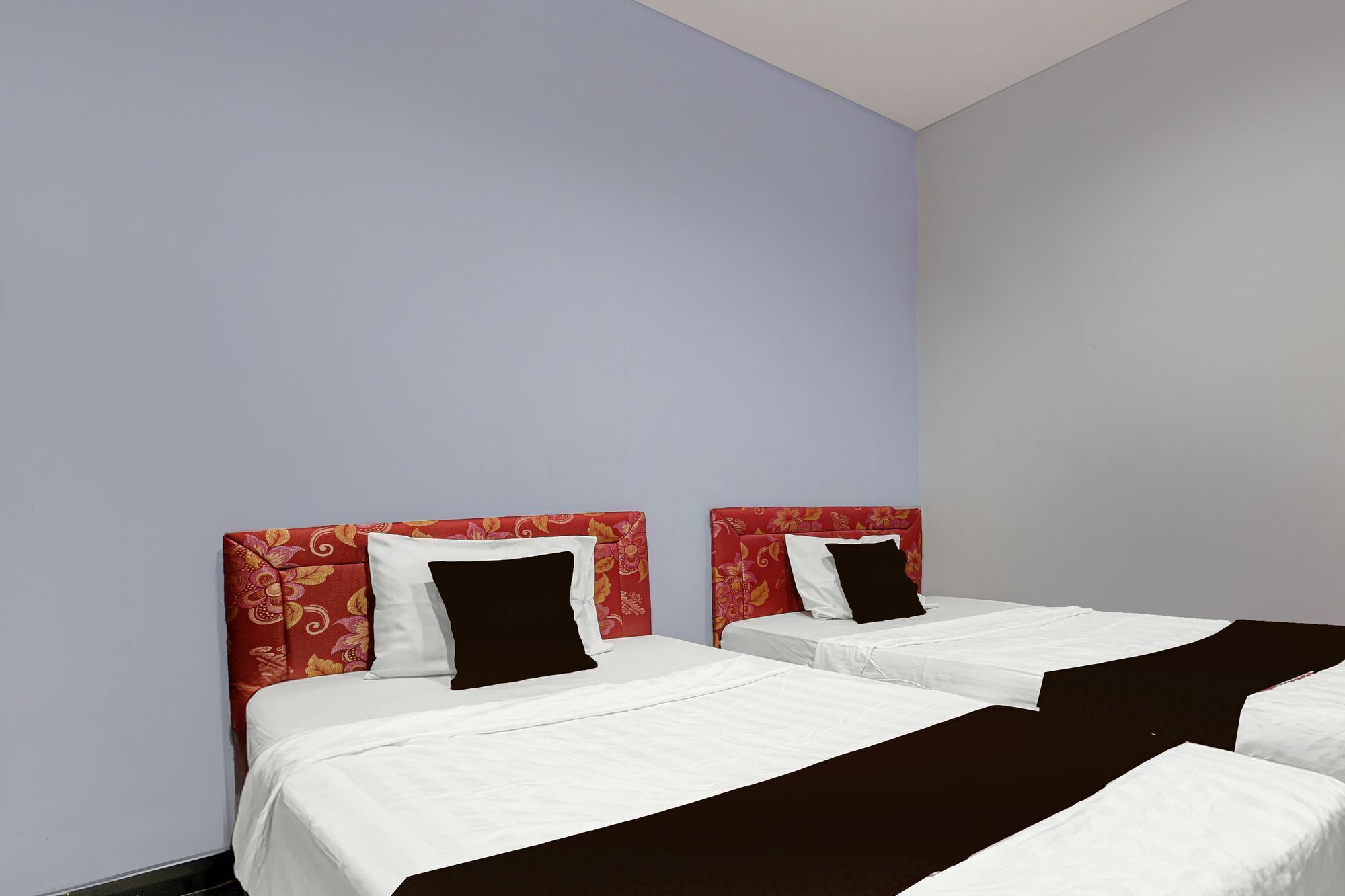 A hotel room with two beds, each with a red headboard and white bedding.