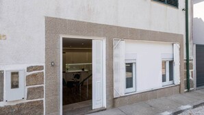 Un bâtiment doté d’une façade en pierre, d’une entrée bien visible et d’une fenêtre avec un store blanc.