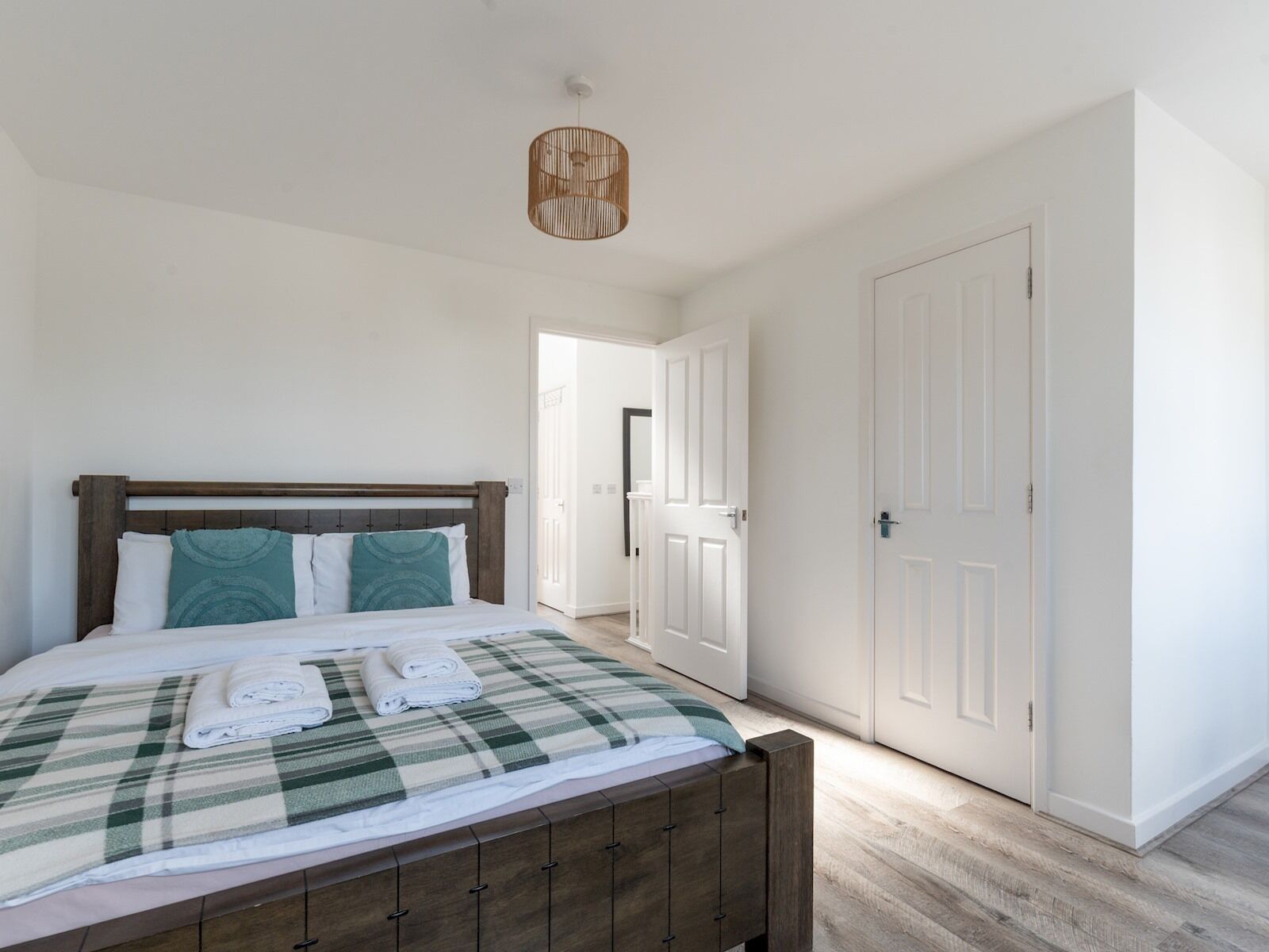 A bedroom with a wooden bed, a checkered blanket, and a hanging light fixture.