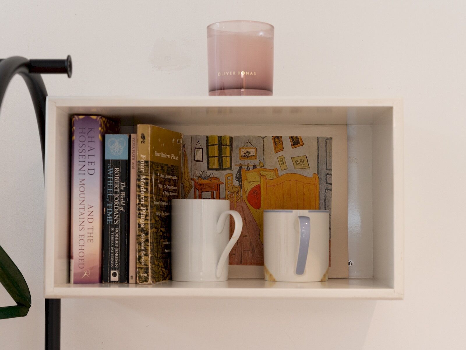 Ein Regal mit Büchern, zwei Tassen und einer Kerze.