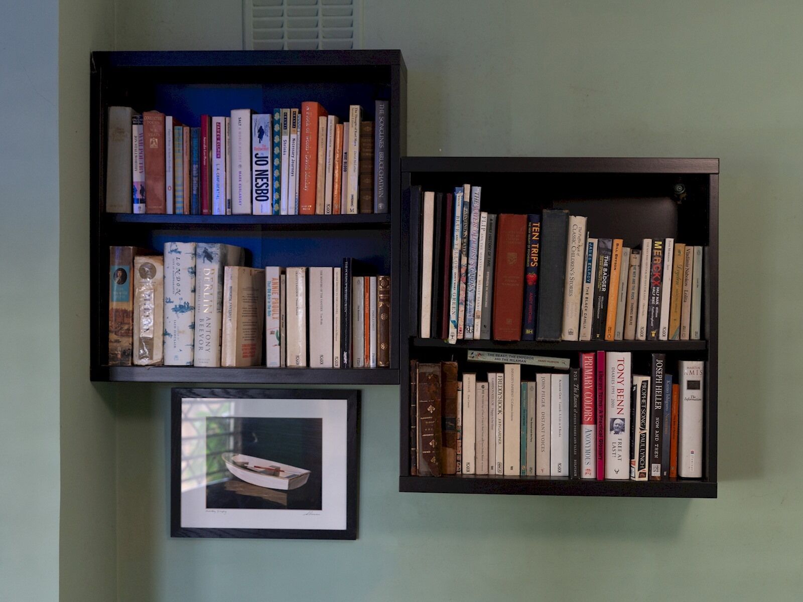 Two bookshelves filled with books against a wall.