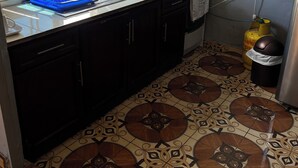 A compact kitchen with a window, a sink, a stove, and a patterned floor.
