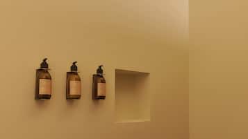 Baño con tres artículos de tocador montados en la pared y un cabezal de ducha.