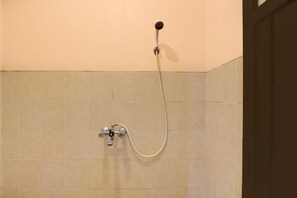 Une douche équipée d’un flexible et d’un robinet de contrôle fixé au mur.