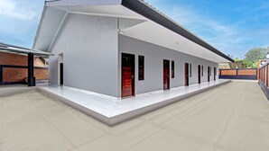A modern building with a flat roof, a covered walkway, and a series of doors. - Hotel O Khayla Homestay Syariah (Giripurwo)