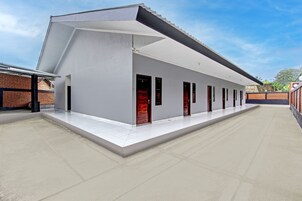 Um edifício moderno com telhado plano, galeria coberta e uma série de portas.