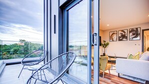 A modern room with a glass door leading to a balcony, a sofa, a small table, and abstract wall art.