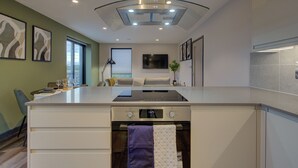 A modern kitchen with a central island, built-in oven, and a large window providing natural light.