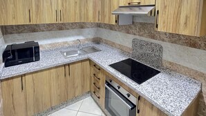Una cucina compatta con mobili in legno, un forno a microonde integrato, un lavello e una stufa.