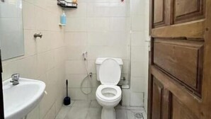 A small bathroom with a toilet, sink, and shower.