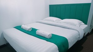 A neatly made bed with white linens and a green accent, a teal headboard, and a white wall. - Hotel O Surau Guest House (Medan)