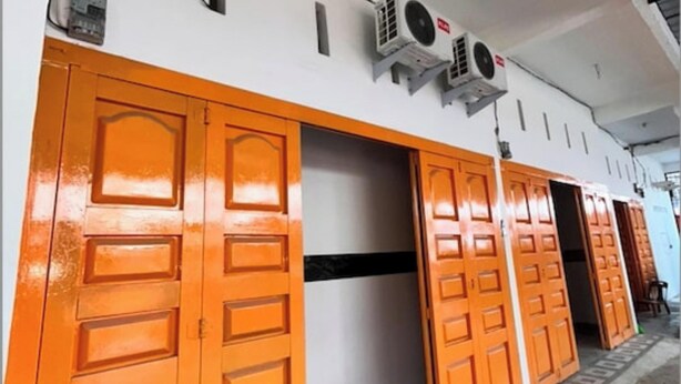 A building with orange doors and air conditioning units mounted on the wall. - Hotel O Surau Guest House (Medan)