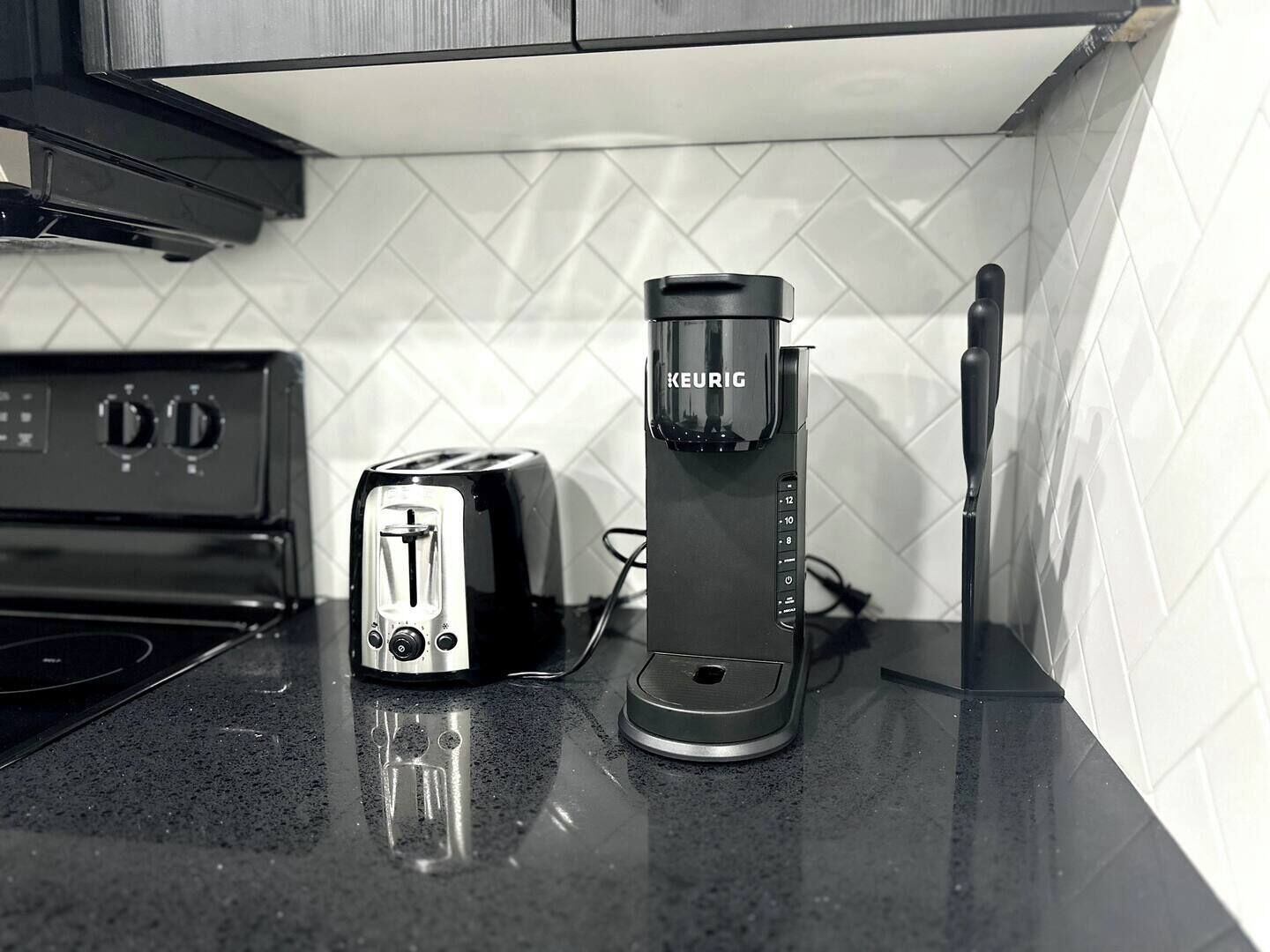 A kitchen with a toaster, a Keurig coffee maker, and a stove.