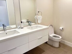 Een moderne badkamer met twee wastafels, een toilet en een grote spiegel.
