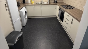 A compact kitchen with a washing machine, a sink, a stove, and cabinets. - 262 Apartments (Leeds)