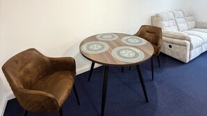 A room with a round table, two chairs, a sofa, and a ceiling light. - 262 Apartments (Leeds)