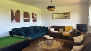 A living room with a pool table, two sofas, a television, and abstract wall art. - Sleeps 11, close to the sea (Tréogat)
