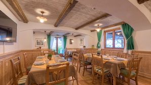 Un comedor con mesas y sillas de madera, techo de madera y una ventana con cortinas.